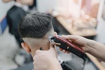 Foto op Canvas Closeup master barber hairdresser does hairstyle with hair clipper and comb. Concept banner Barbershop for man © Parilov