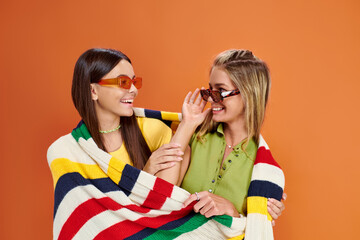 joyous adorable teenage girls with sunglasses hugging and covering with blanket, friendship day