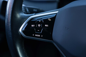 Close up of steering wheel of a new electric vehicle. Electric car control devices. Cruise control...