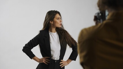 Backstage of model and professional team in the studio. Close up of appealing model in suit posing,...