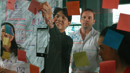 Portrait of professional business team brainstorming marketing idea by using sticky notes to share...