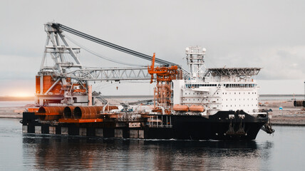 Wind Generators And Offshore Construction Crane Vessel With The Cargo Of Monopiles On Deck. Ship...