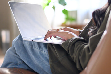Woman wearing white shirt typing work on laptop on desk