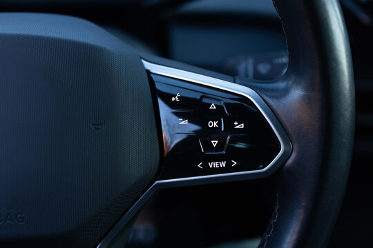 Close-up view of car interior. View of steering wheel of car control music. Volume button of car radio on steering wheel. Turns up the volume of the music in the car.