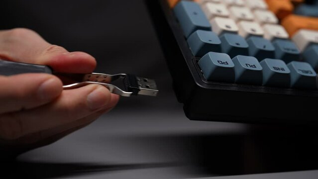 Close-up hands of unrecognizable man using special clip takes out USB receiver to connect keyboard wirelessly. Male PC user prepping new mechanical gaming RGB keyboard with stylish keycaps ready to go