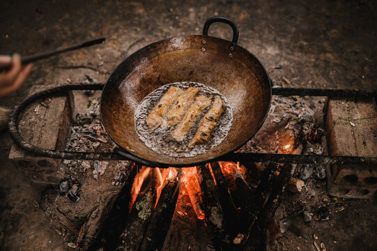 Anonymous person frying spring rolls with pan