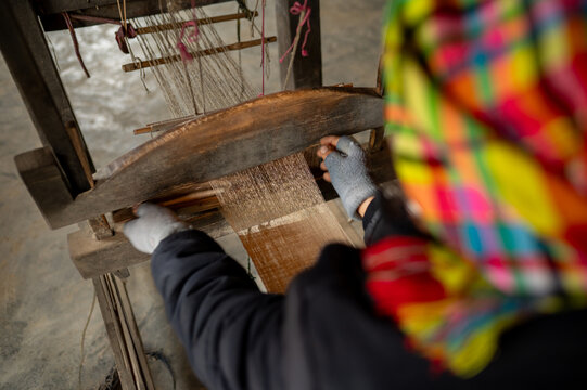 Crop person weaving with traditional loom in workplace