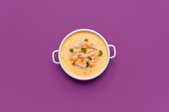 Greek chicken soup above view, minimalist on a purple background