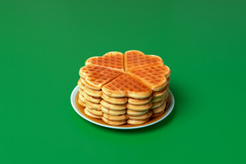 Waffles with mapple syrup on a plate, isolated on a green background