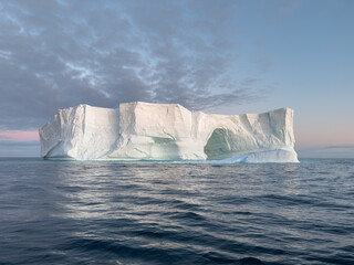 A huge high breakaway glacier drifts in the southern ocean off the coast of Antarctica at sunset,...