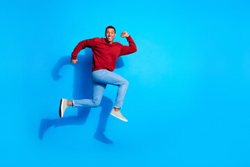 Fototapeta na wymiar Full length profile portrait of handsome man jump rush empty space ad isolated on blue color background