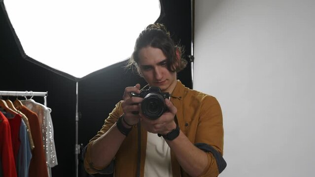 Model and production team in the studio. Young man professional photographer taking picture looking directly at camera.