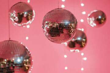 Shiny disco balls hanging on a pink background,. Generative AI
