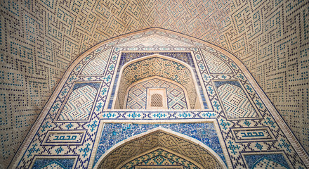 Element of the facade of a madrasah made of brick with mosaic cladding in the ancient city of Bukhara in Uzbekistan, architecture in oriental style, facade of a mosque with patterns and ornaments