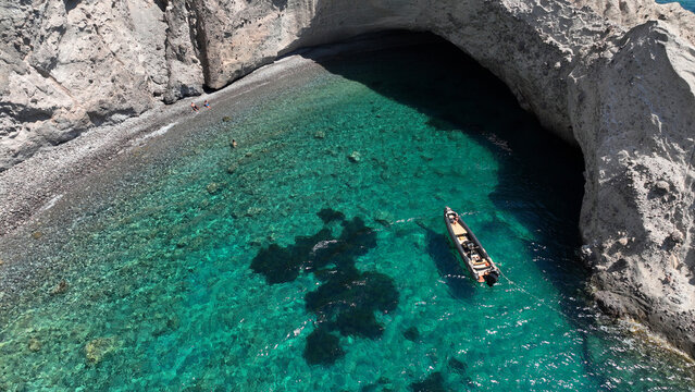 Aerial drone photo of beautiful crystal clear turquoise beach and cave formations visited by yachts and sail boats in Southern part of Antiparos island, Cyclades, Greece