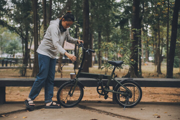 Obraz premium Happy Asian young woman walk and ride bicycle in park, street city her smiling using bike of transportation, ECO friendly, People lifestyle concept.