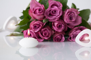 Beauty products background with wooden heart light, spa candle burning, bouquet of purple roses and nice reflection. Studio shot.