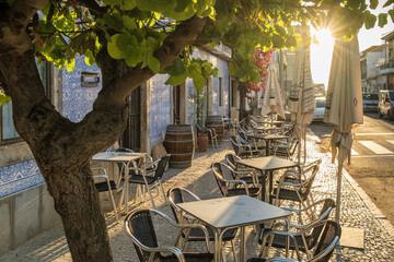 Outdoor cafe on a beautiful street with traditional azulejos Portuguese houses in Tavira