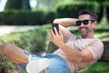 mature man taking selfie while sitting on a bench