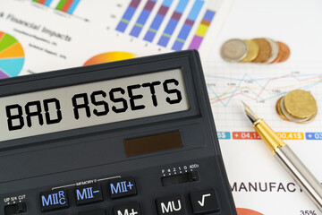 On the table are financial reports, coins and a calculator with the inscription - bad assets