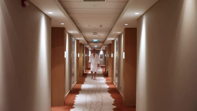 Man in bathrobe go on corridor of hotel, slow motion. 