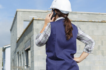 mid-adult woman talking on a cellphone at a construction site