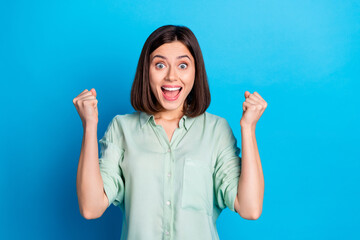 Portrait of overjoyed girl with stylish hairdo wear turquoise blouse clenching fists scream win bet...