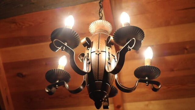 Metal chandelier with five lamps on a wooden ceiling
