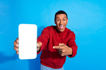 Portrait of astonished cheerful guy indicate finger demonstrate empty space smart phone screen...