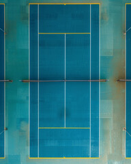 Aerial view of an empty badminton court with blue flooring and vibrant yellow lines