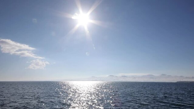 Sun floods with light lake Sevan and snow mountain afar in Armenia.