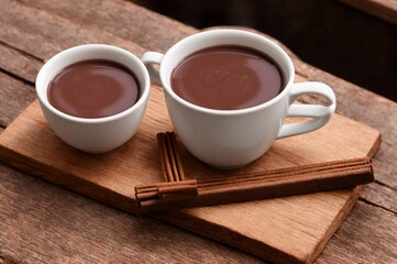 Cup of hot chocolate with cinnamon on wooden table, closeup