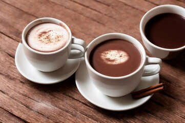 Obraz premium Cup of hot chocolate with cinnamon on wooden table, closeup