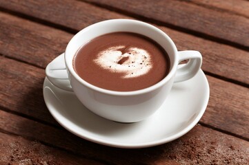 Cup of hot chocolate with cinnamon on wooden table, closeup