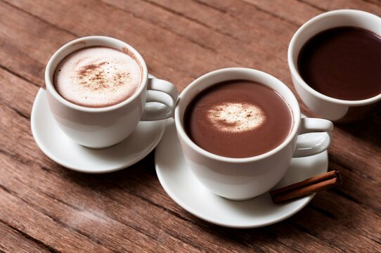 Cup of hot chocolate with cinnamon on wooden table, closeup