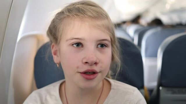Face of girl singing song and smiling in flying airplane close up.