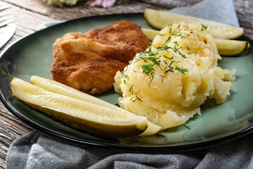 Pork chop served with mashed potatoes and pickled cucumber.
