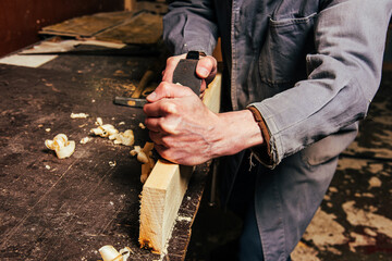 A carpenter works in a workshop with a saw, planer and various tools - obrazy, fototapety, plakaty