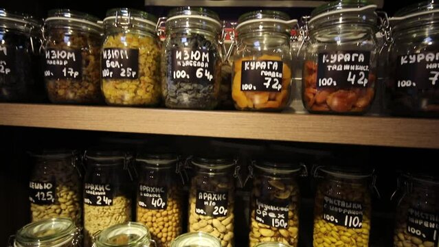 Different nuts in jars in store, translation of text - cedar nuts, seeds, etc
