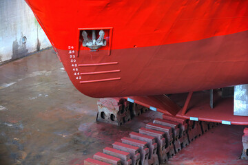 Close up view of the hull with anchor of a bright red ship in a covered dry dock 