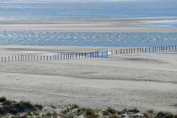 Panoramic view of the Maasvlakte beach near Rotterdam with tide pools and long fence on the sand...
