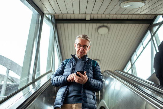 Senior man using a smartphone in a train station