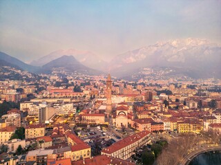 Drone shot of the city of the center of Lecco city and Basilica di San Nicolò, Italy. Mount Resegone in the background