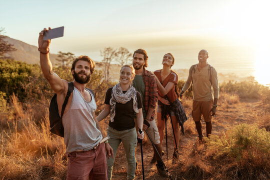 Diverse group of young hikers taking a selfie with smartphone in south africa