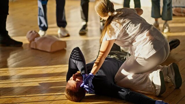 A professional nurse girl demonstrates a change in the position of a lying person during medical care. Practical training of a physician