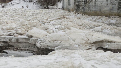 rearing ice floes on the river near the bridge support pylon before the start of the ice drift
