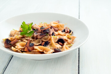 Piatto di pasta condita con funghi, olio di oliva e prezzemolo, cibo italiano 
