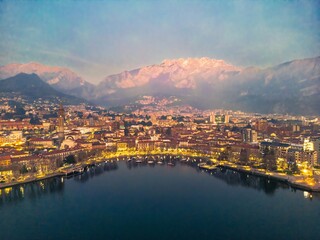Drone shot of the city of Lecco and Lake Como in the evening, Italy. Mount Resegone in the background