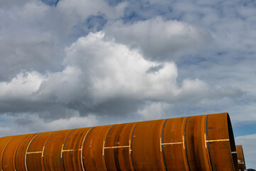 Obraz premium Close up of corroded or rusted conical and tubular steel towers for wind turbines (windmill) in horizontal position on construction site
