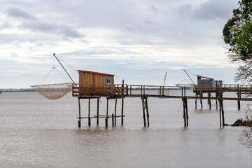 Fototapeta na wymiar View of traditional fishing huts on stilts with suspended carrelets (fishing nets) along the Gironde Estuary near Bordeaux, France